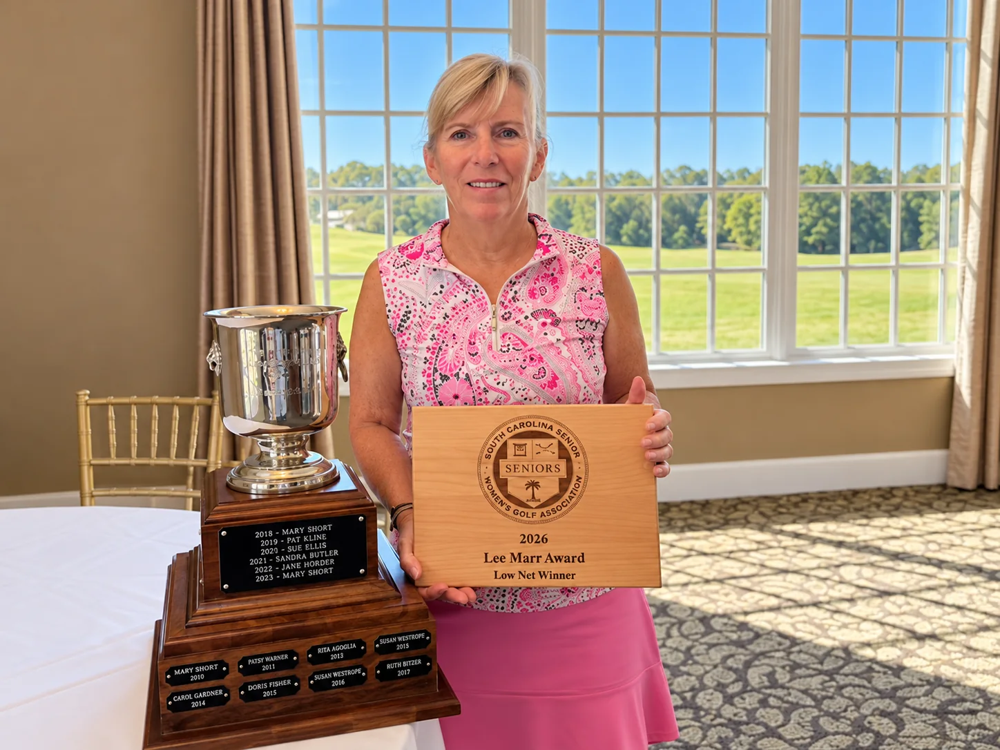 Doris Fisher holding the Lee Marr Award plaque beside the trophy